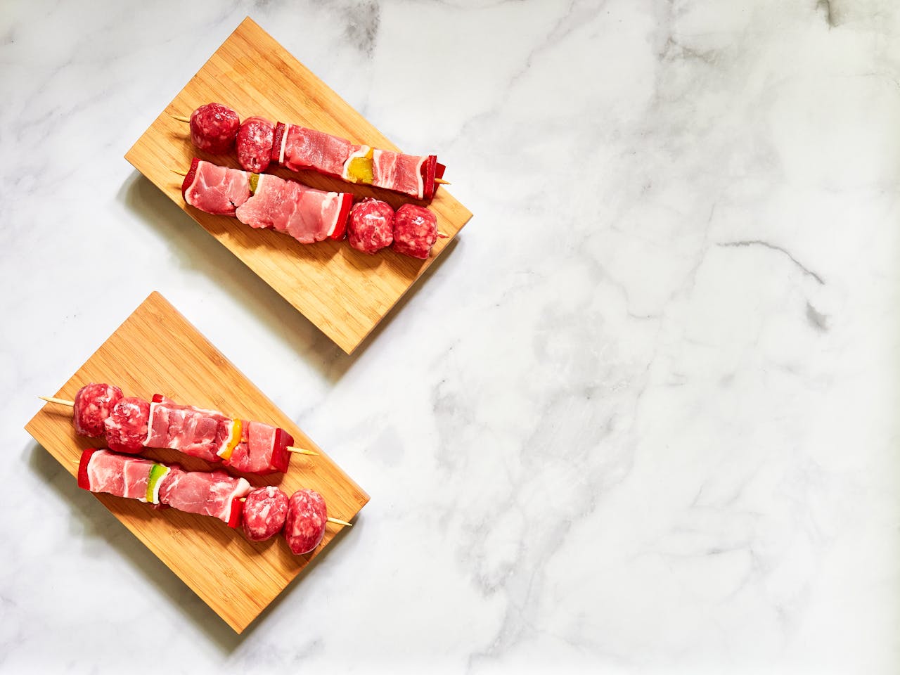 Home Top view of raw meat skewers on wooden boards ready for grilling, emphasizing freshness and preparation.